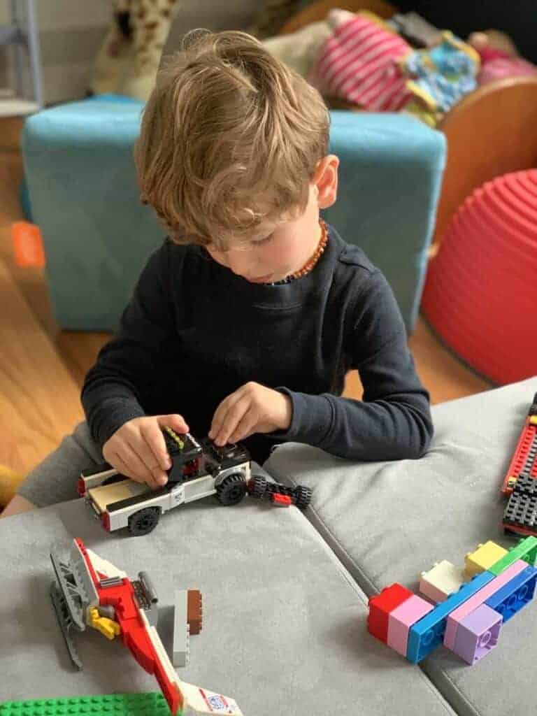 A boy is playing with Lego style blocks improving his imagination and growth. 