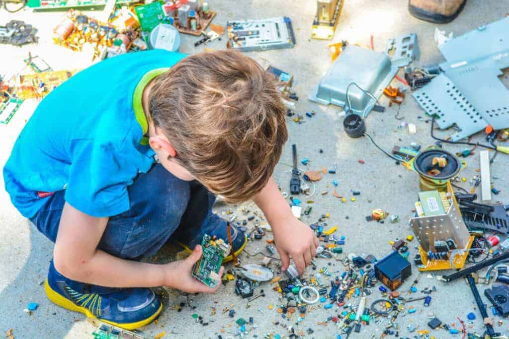 A child combing through old processor boards and computer parts with interest.