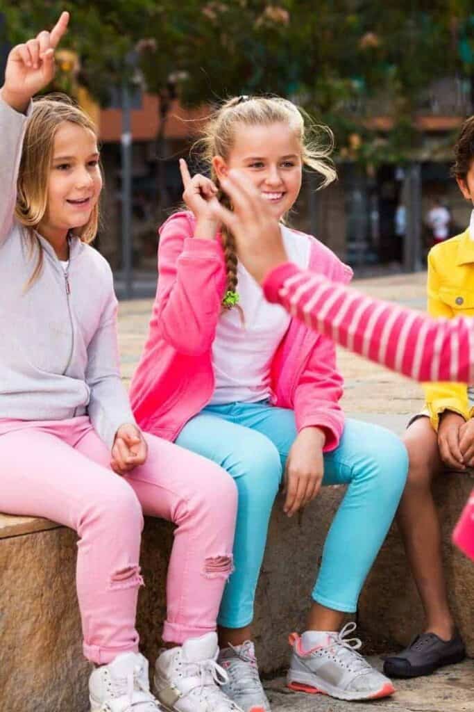 Children sitting on a wall playing together representing Socratic seminar. 