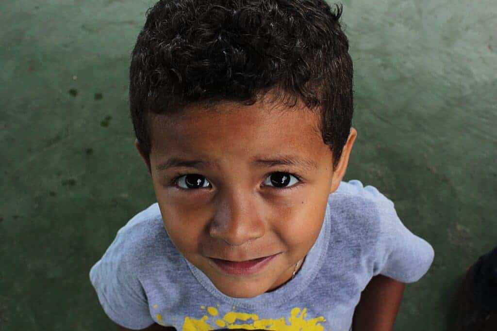 A little boy looking up at the camera lens looking like he is about to ask a question.