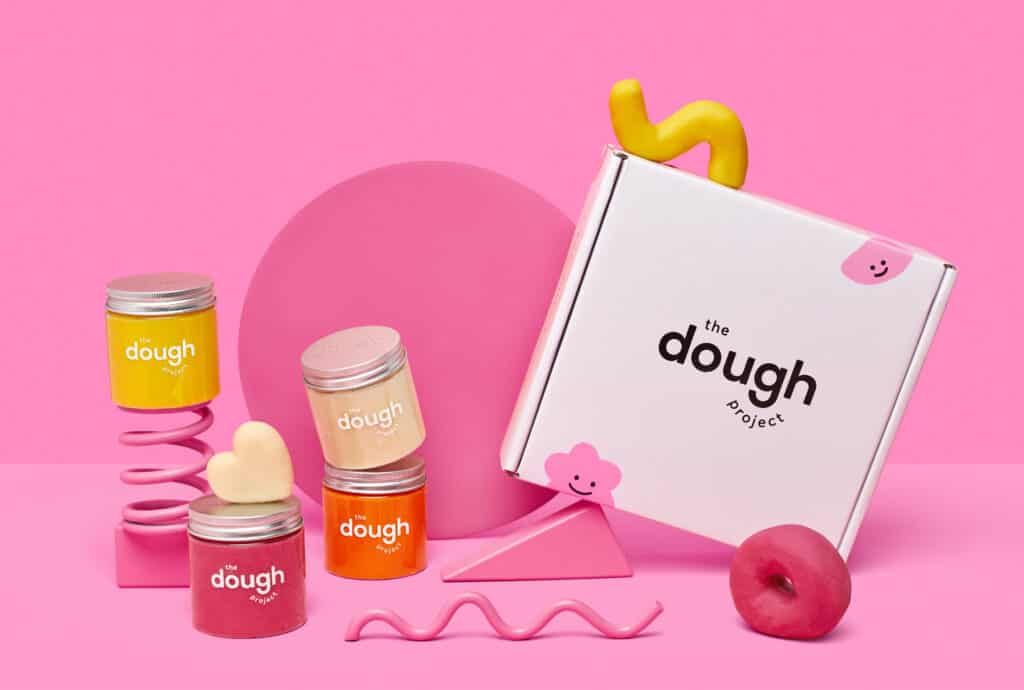 The dough project play dough shipping box with red, orange and yellow jars of dough surrounding the box