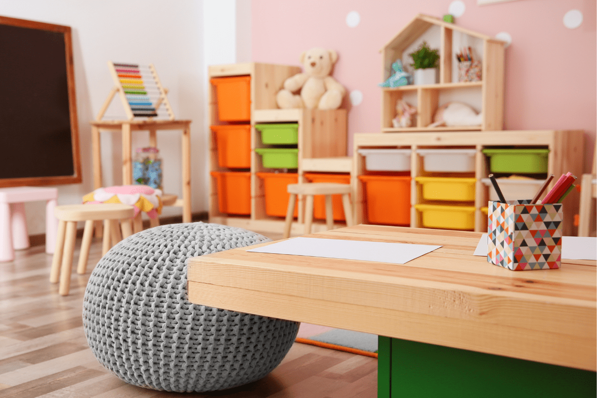 a large wooden table featured in a playroom with storage bins for toys