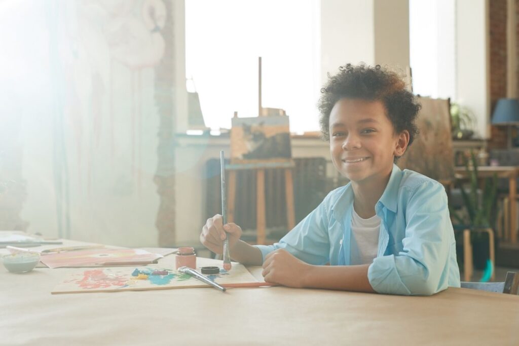 Black boy sitting at a desk doing art