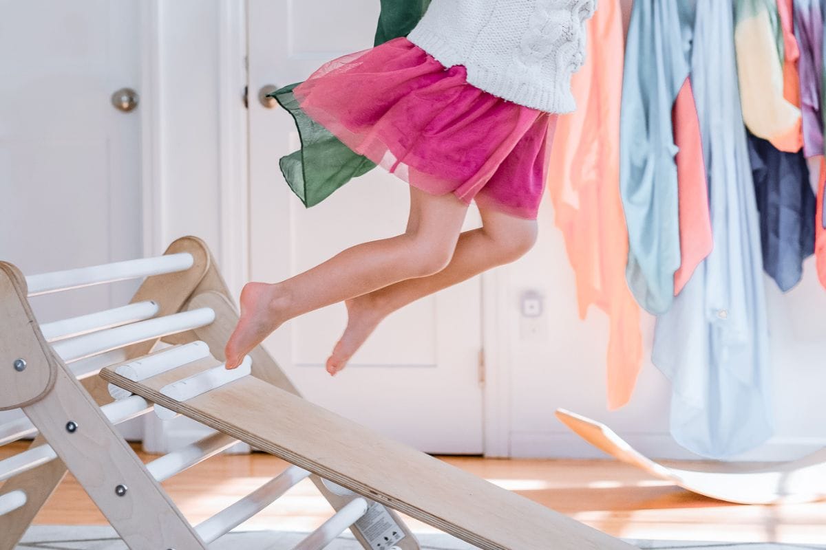 child jumping off a pikler triangle